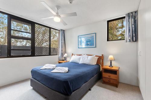 a bedroom with a blue bed and a window at Sea Point Ocean Apartments in Caloundra