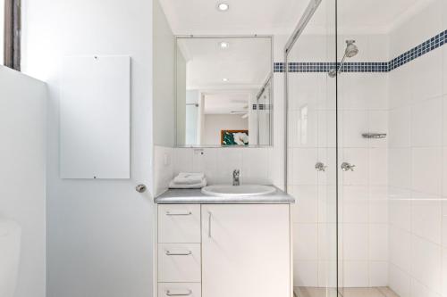 a white bathroom with a sink and a shower at Sea Point Ocean Apartments in Caloundra
