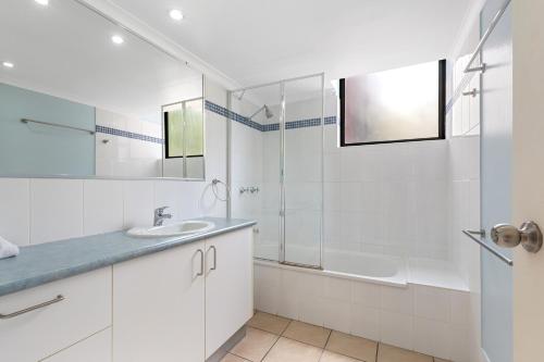 a white bathroom with a shower and a sink at Sea Point Ocean Apartments in Caloundra