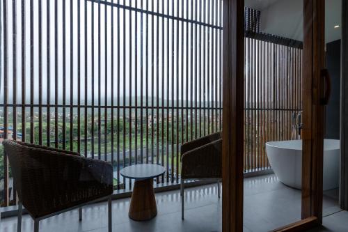 a bathroom with a large window with a tub and a table at Radisson Resort and Spa Lonavala in Lonavala
