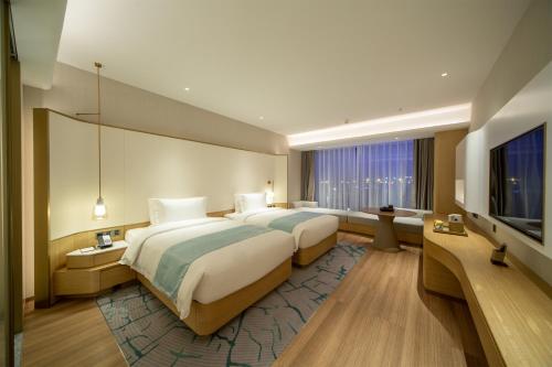 a hotel room with two beds and a flat screen tv at Wyndham Garden Jinjiang in Jinjiang