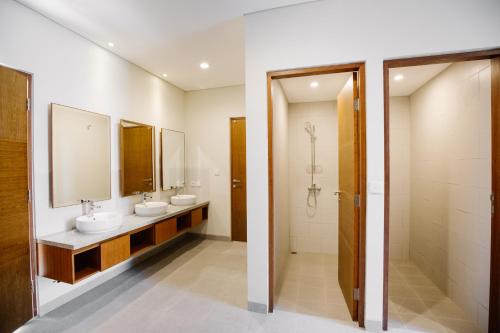 a bathroom with two sinks and a mirror at Vasudha Hostel Canggu in Canggu