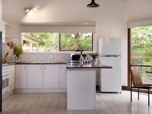 a kitchen with white cabinets and a white refrigerator at Serena- a stone's throw from Lake Daylesford in Daylesford