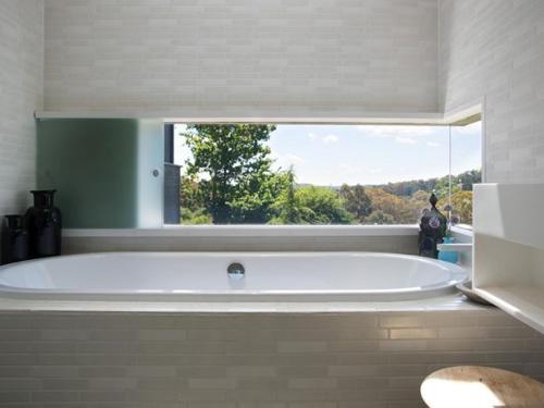 a large white tub in a bathroom with a window at Harts Lane Stag and Millies in Daylesford