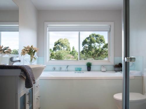 baño con bañera blanca y ventana en Della Fonte, en Daylesford