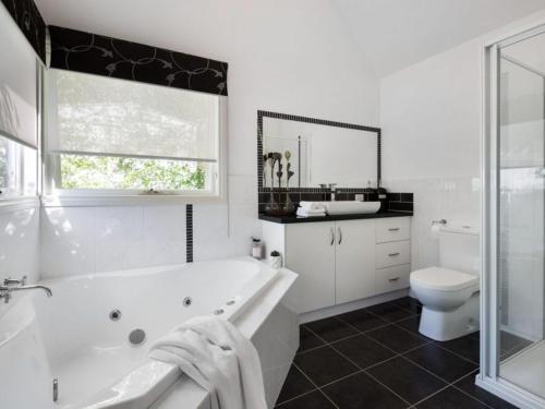 La salle de bains blanche est pourvue d'une baignoire et de toilettes. dans l'établissement Cottage 4A, à Daylesford