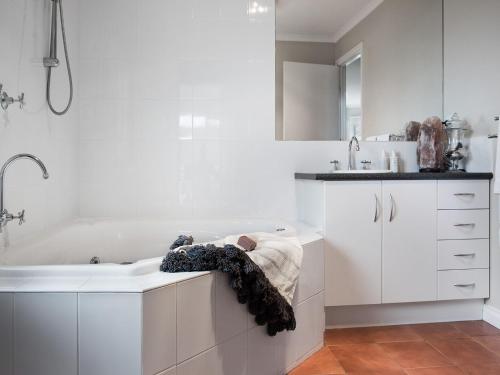 a white bathroom with a tub and a sink at Accolade in Daylesford