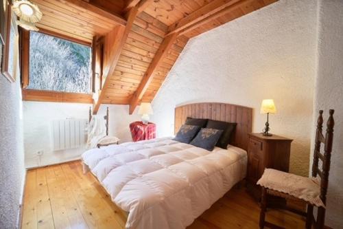 a large bed in a bedroom with a wooden ceiling at Apartment 3 bedrooms with ski locker and parking at Baqueira-Beret in Arties