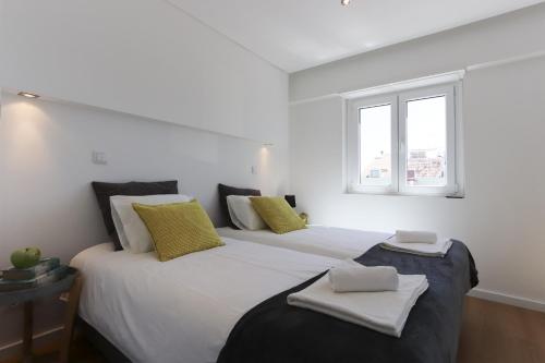 リスボンにあるMarques Premium by Homingのベッドルーム1室(黄色と白の枕が備わるベッド2台付)