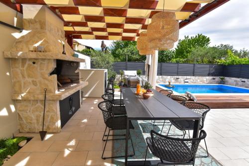 a patio with a table and chairs and a grill at Villa Teuta ZadarVillas in Zadar