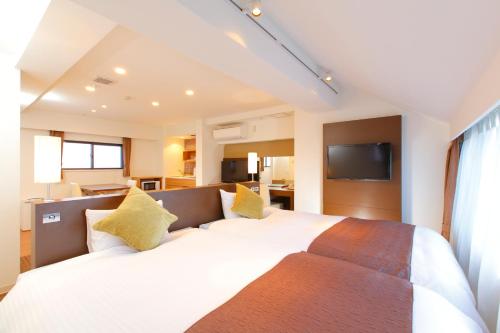 a bedroom with a large white bed with yellow pillows at FLEXSTAY INN Iidabashi in Tokyo