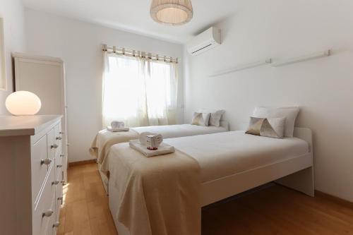 ein weißes Schlafzimmer mit 2 Betten und einem Fenster in der Unterkunft Expo Delight by Homing in Lissabon