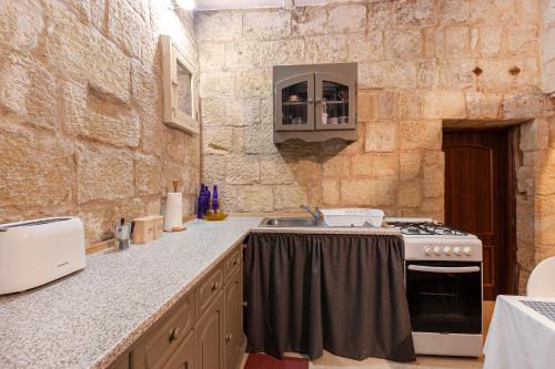 a kitchen with a stove and a stone wall at BRG34 - Historical Vittoriosa Townhouse in Vittoriosa