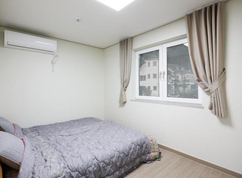 a bedroom with a bed and a window at Herkules Namhae German Village in Namhae
