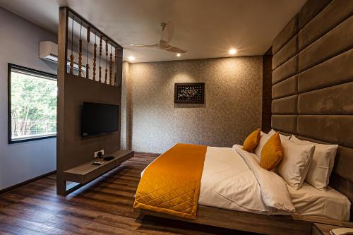 a bedroom with a large bed and a television at Regenta Inn Sambalpur, Farm Road in Sambalpur