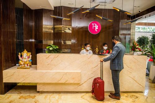 a man with a suitcase waiting at a counter in a hotel at Regenta Inn Sambalpur, Farm Road in Sambalpur