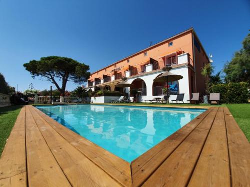 a swimming pool in front of a building at Hôtel Athéna in Agde