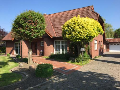 een rood bakstenen huis met twee bomen ervoor bij Ferienwohnung Vereinswiek 95137 in Rhauderfehn