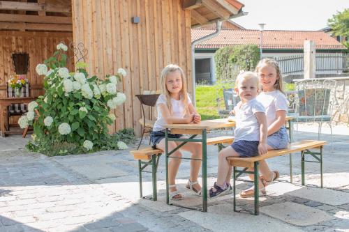 three children sitting at a table in a backyard at Ferienhof Naderhirn - Bauernhof in Wegscheid