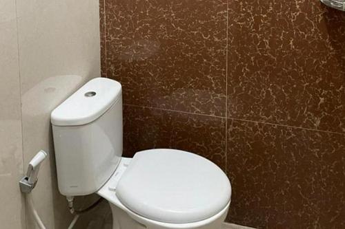 a bathroom with a white toilet and a brown wall at Villa Syariah Citeko Mitra RedDoorz in Bogor