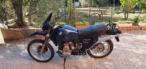 a blue motorcycle parked on a gravel road at Orto degli Ulivi in Sinalunga
