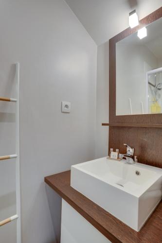 une salle de bain avec un lavabo blanc et un miroir dans l'établissement Le Richelieu, à Versailles
