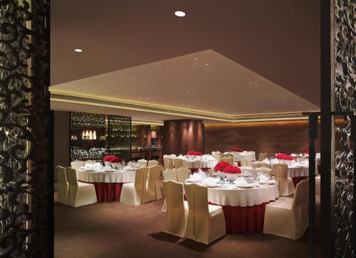 a dining room with white tables and white chairs at New World Dalian Hotel in Dalian