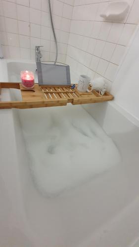 estante de madera en el baño con lavabo y vela en Appart'Hotel Lizon Cocooning avec sauna, en Lavans-lès-Saint-Claude