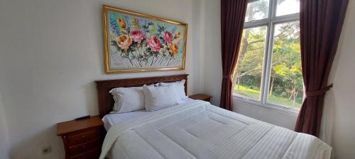 a bedroom with a bed with a picture on the wall at Vila Dalia Puncak Nb4-01 in Cikundul