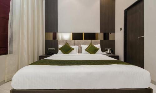 a bedroom with a large white bed with green pillows at Hotel Oyster Suite Andheri West in Mumbai