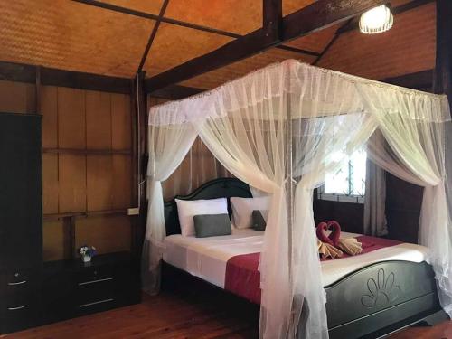 a bedroom with a canopy bed with white curtains at Kohjum Seafront Resort in Ko Jum