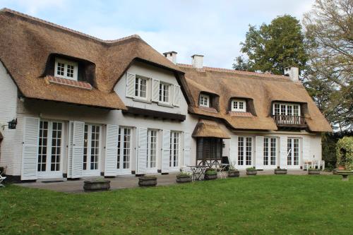 a large white house with a thatched roof at Villa Monceau Louvain la neuve in Louvain-la-Neuve