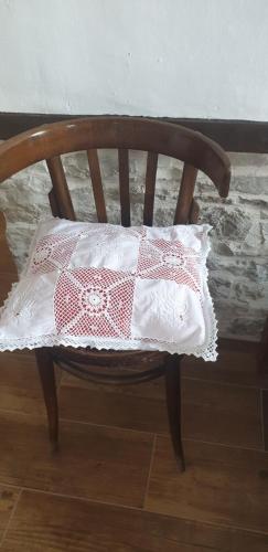 a wooden chair with a red and white pillow on it at Silver Hill Guesthouse in Gjirokastër