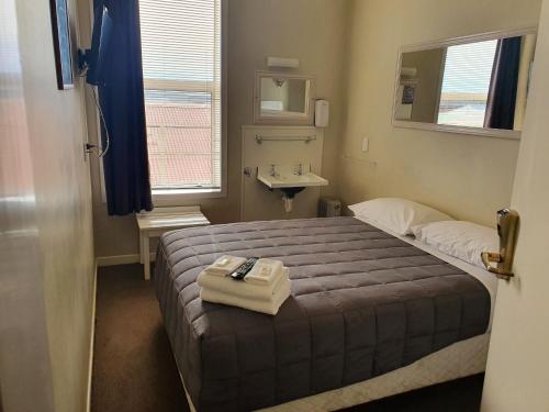 um pequeno quarto com uma cama e um lavatório em Fernlodge Inglewood em Inglewood