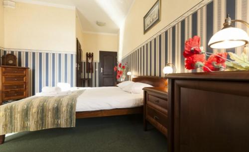 a bedroom with a bed and a wooden dresser and a dresser at Sieć Hoteli Fort Warszawa in Warsaw