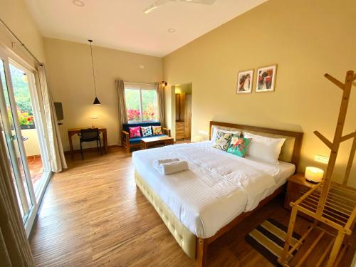 a bedroom with a large bed with white sheets at Flower Valley Plantation Homestay in Munnar