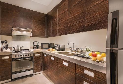 a kitchen with wooden cabinets and a sink with fruit on the counter at Aruga Apartments by Rockwell Makati in Manila