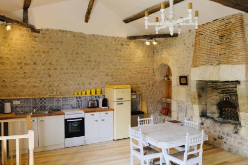 cocina con mesa y pared de ladrillo en As seen on A New Life in The Sun - Beautiful 3 bedroom cottage with shared pool, en Montboyer