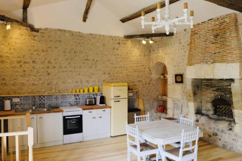 une cuisine avec une table et un mur en briques dans l'établissement As seen on A New Life in The Sun - Beautiful 3 bedroom cottage with shared pool, à Montboyer