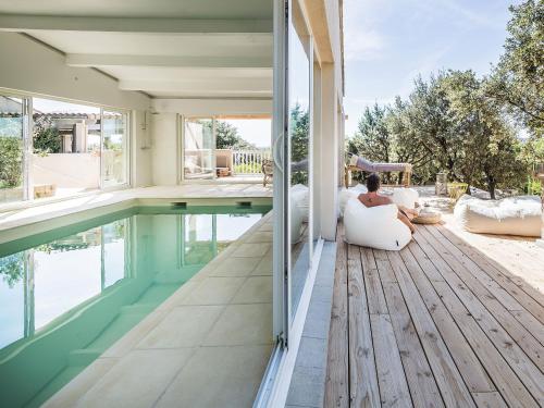 una mujer sentada en el porche de una casa con piscina en La Villa Les Petits Gardons, en Castillon-du-Gard