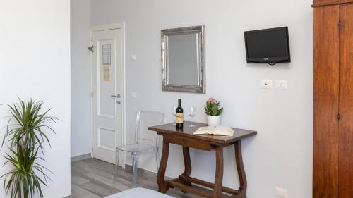 a room with a table with a bottle of wine and a tv at Hotel Villa Bonelli in Fiesole