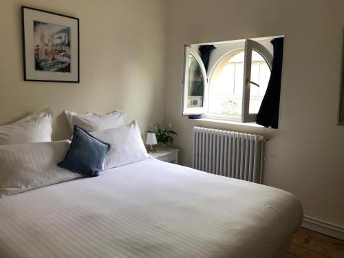 a bedroom with a large white bed with a window at Le Rodin Bazas in Bazas
