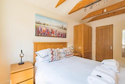 Un dormitorio con una cama blanca y una pintura en la pared en The Roost by Bloom Stays en Wingham