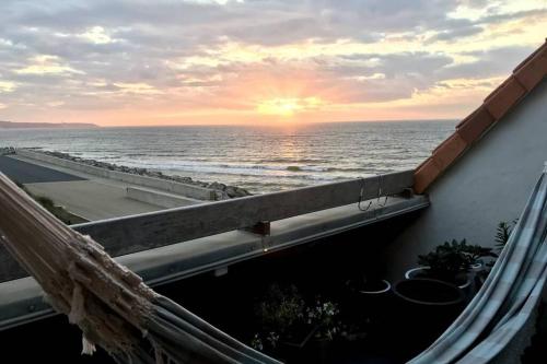 d'un balcon offrant une vue sur l'océan au coucher du soleil. dans l'établissement DUPLEX AVEC JACUZZI vue imprenable sur la baie de Wissant, à Wissant