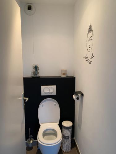 een badkamer met een toilet met een zwart-wit gezicht op de muur bij Appartement F2 Salines de Porto Vecchio in Porto-Vecchio