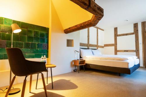ein Schlafzimmer mit einem Bett, einem Tisch und einem Stuhl in der Unterkunft Resort Schloss Rued in Schlossrued
