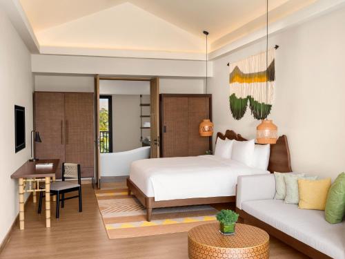 New World Phu Quoc Resort في فو كووك: غرفة نوم بسرير ومكتب واريكة