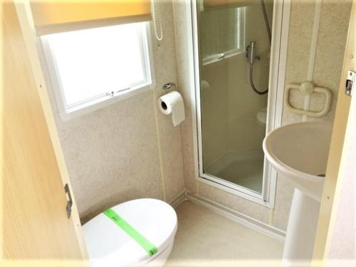 a bathroom with a toilet and a shower and a sink at Devon Barnstaple Self Catering Accommodation Tarka Holiday Park, A14 Free Wi-Fi Spacious Tarka Holiday Park sleeps 5 Pets allowed Static Caravan home Devon EX31 4AU just 6 miles from Saunton Sands in Barnstaple