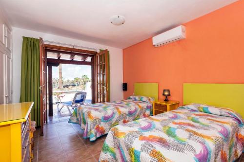 two beds in a room with orange walls at Casa Bonita, Golf del Sur in San Miguel de Abona