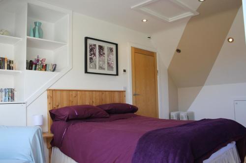 a bedroom with a bed with a purple blanket at Cherry Trees in Stowmarket